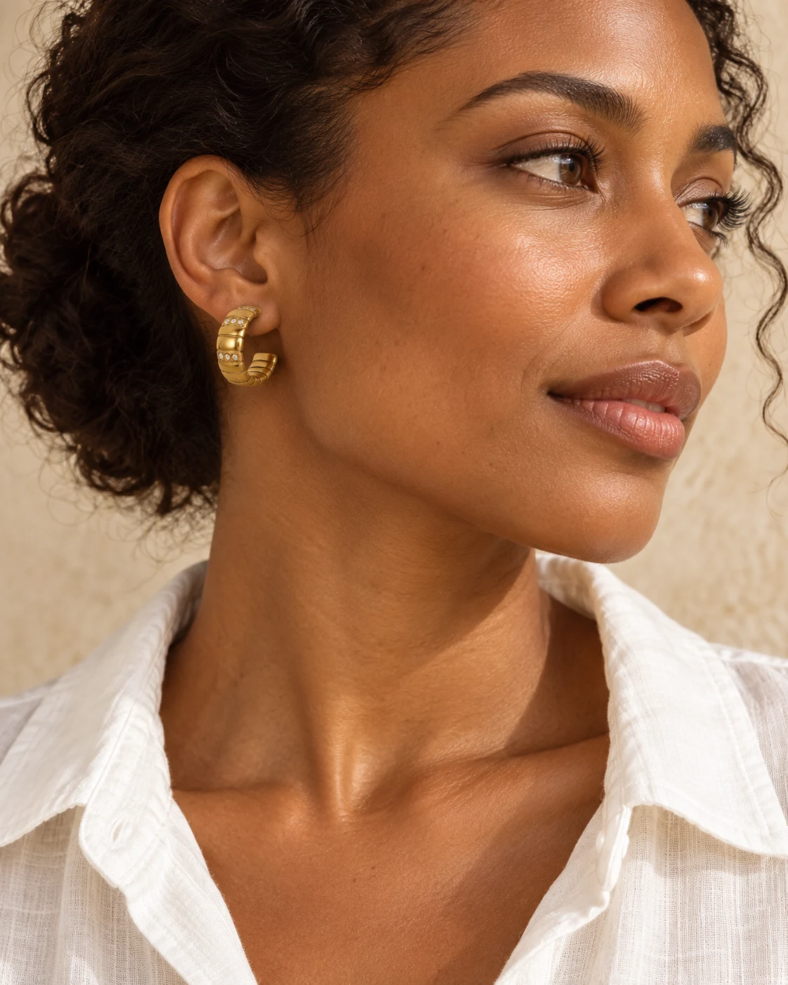 Editorial styling illustration of a woman wearing gold-tone hoop earrings